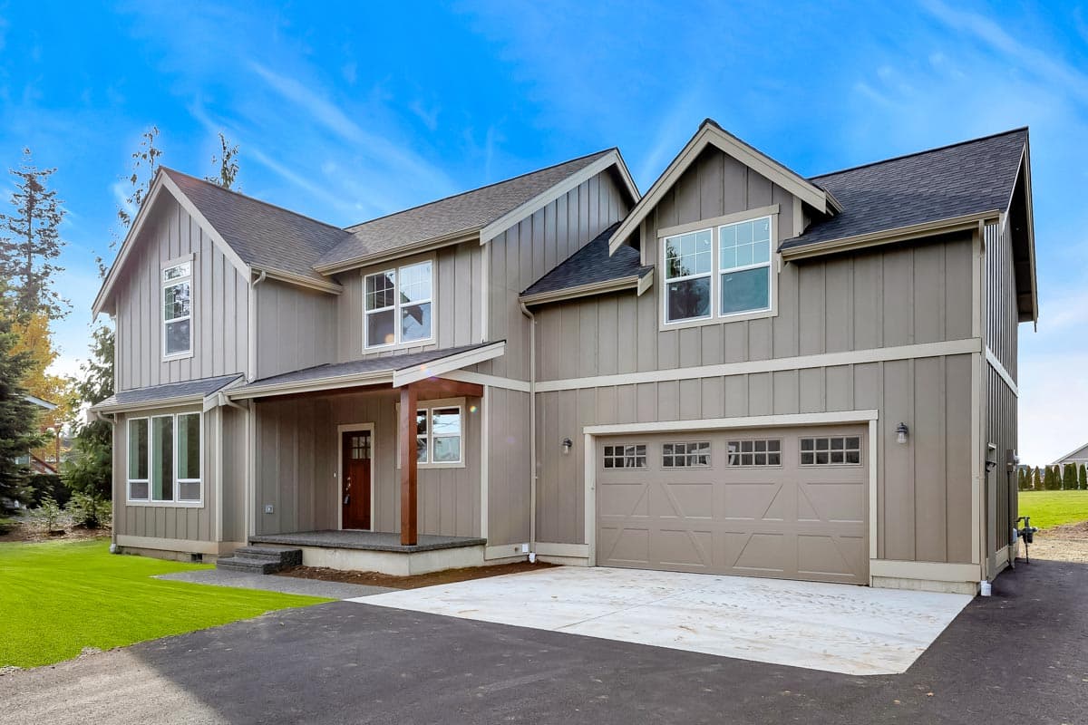 House plan exterior of a two-story home with vertical siding, covered porch, and attached garage with glass-paneled door.