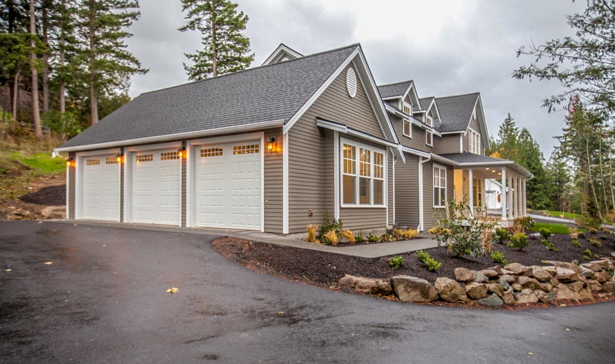 House plan exterior with a three-car garage, gabled dormers, and a covered front porch supported by columns.