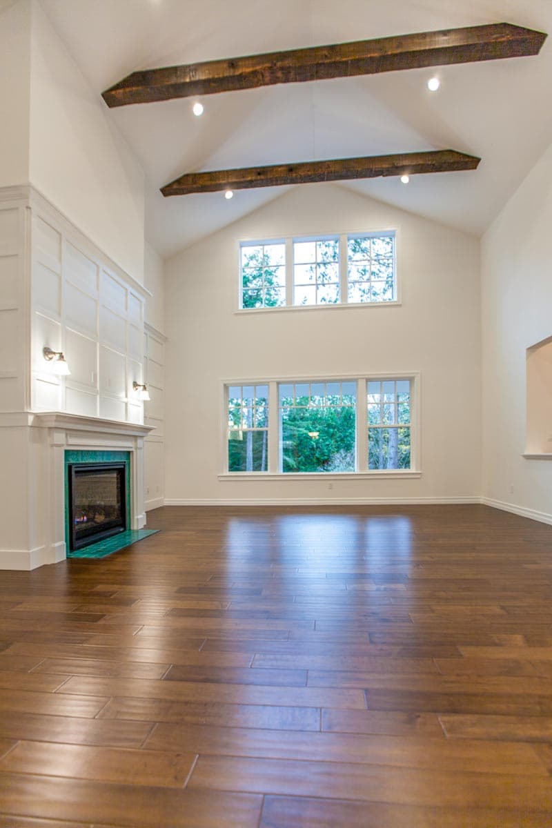Interior view: Great room with fireplace, wood beams, and large windows. Vaulted ceiling.