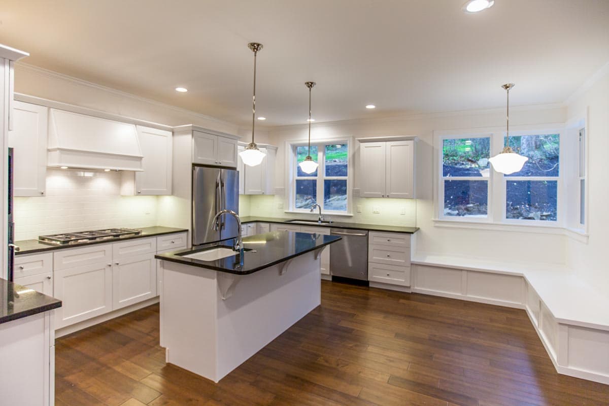 Kitchen with island, stainless steel appliances, gas range, subway tile backsplash, and bay window seating.