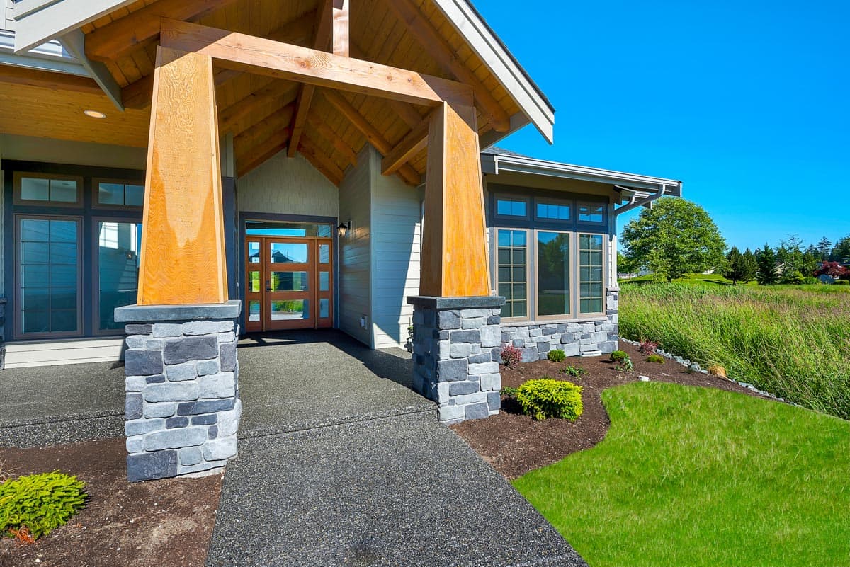 House plan exterior with timber-framed entry, stacked stone accents, and horizontal siding.