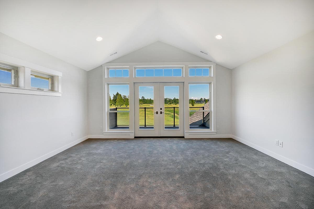 Interior rendering of a room with vaulted ceiling, large windows, and double doors opening to a balcony with a view.