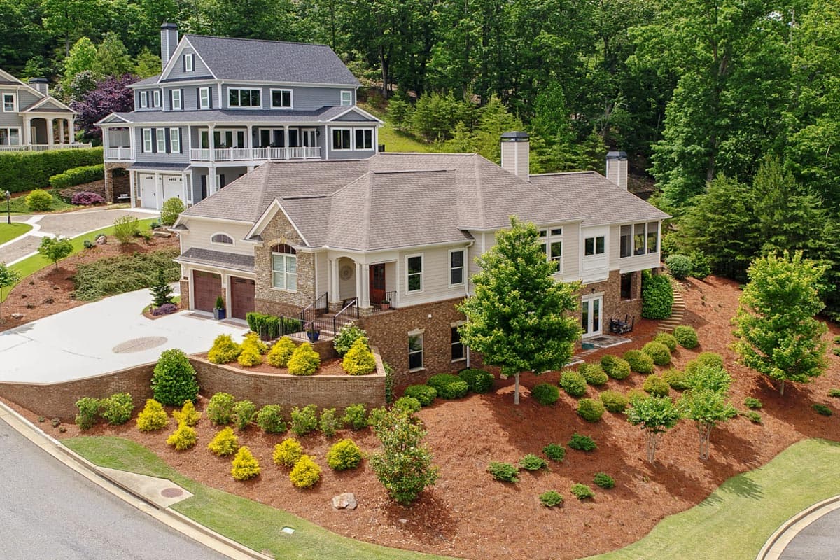 House plan exterior: Two-story home with multiple gables, a porte-cochère, and a prominent stone entryway.
