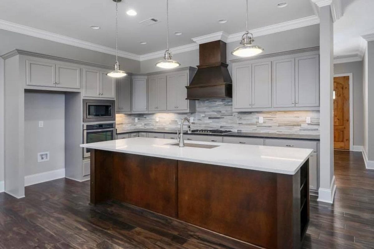 Kitchen with grey cabinets, dark wood island, white quartz counters, stainless steel appliances, and tile backsplash.