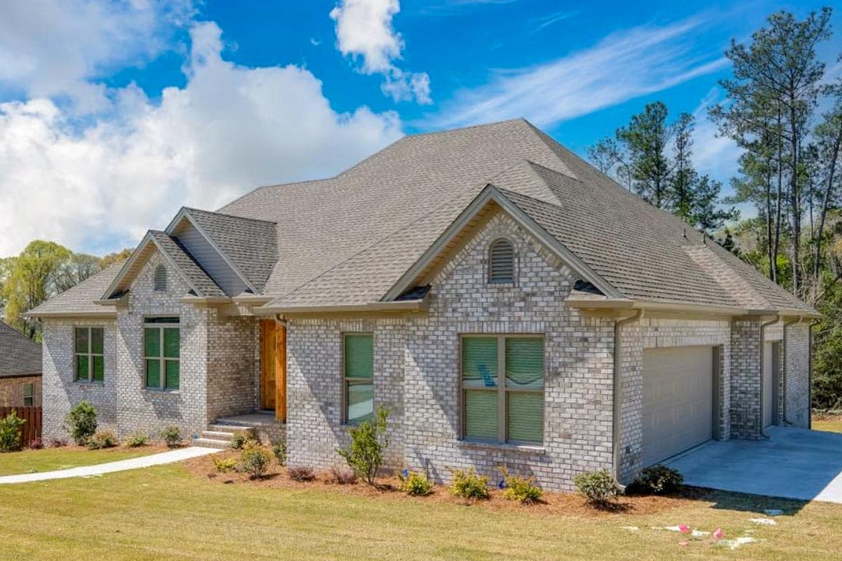 House plan exterior: Single-story brick home with multiple gables, front porch, and a side-entry garage.