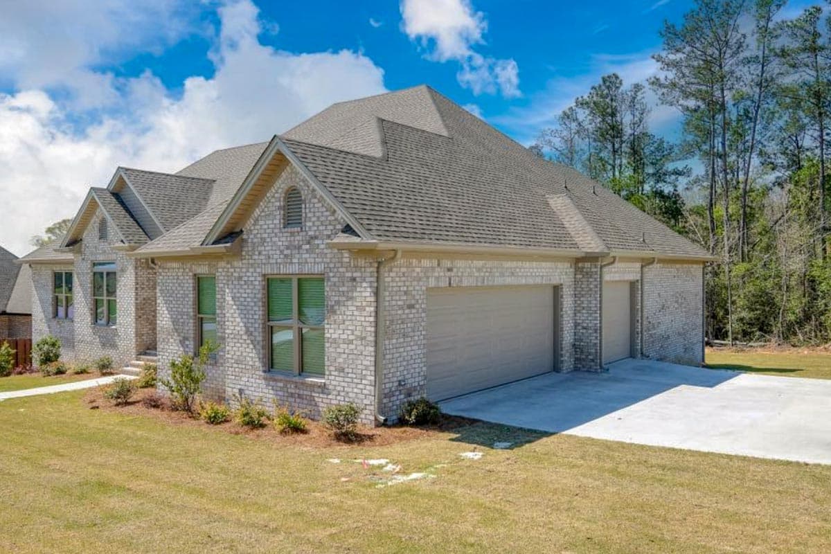 House plan exterior: One-story brick home with gabled dormers, a triple garage, and pitched rooflines.