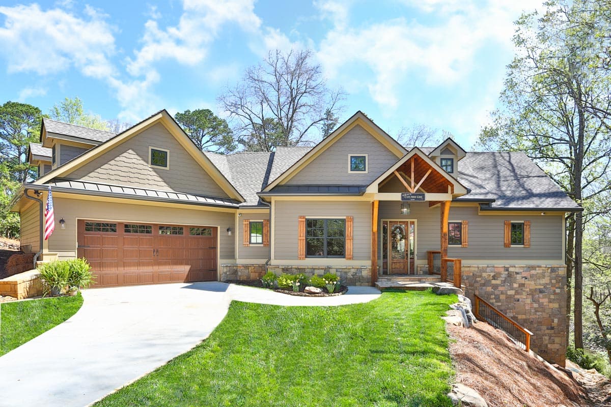 Craftsman house plan exterior with a two-car garage, prominent gables, stone accents, and a covered entry porch with wood supports.