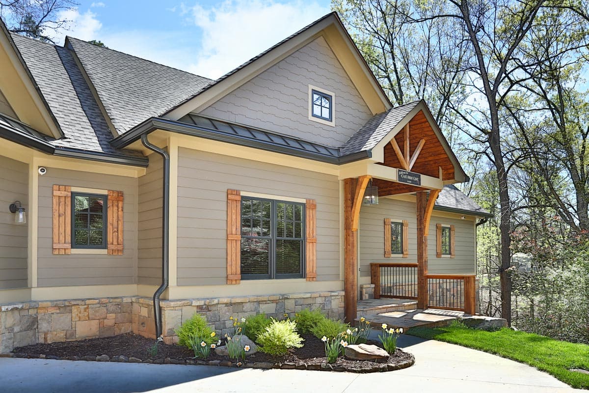 Modern Farmhouse house plan exterior with stone foundation, gable dormers, and exposed wood beams on covered porch.