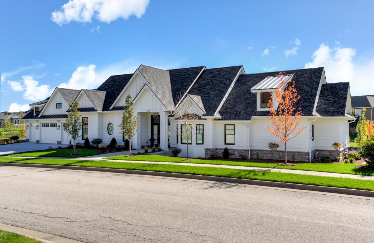 House plan exterior featuring a two-story Modern Farmhouse design. Includes gable roof, dormers, and attached garage. White siding with black trim.