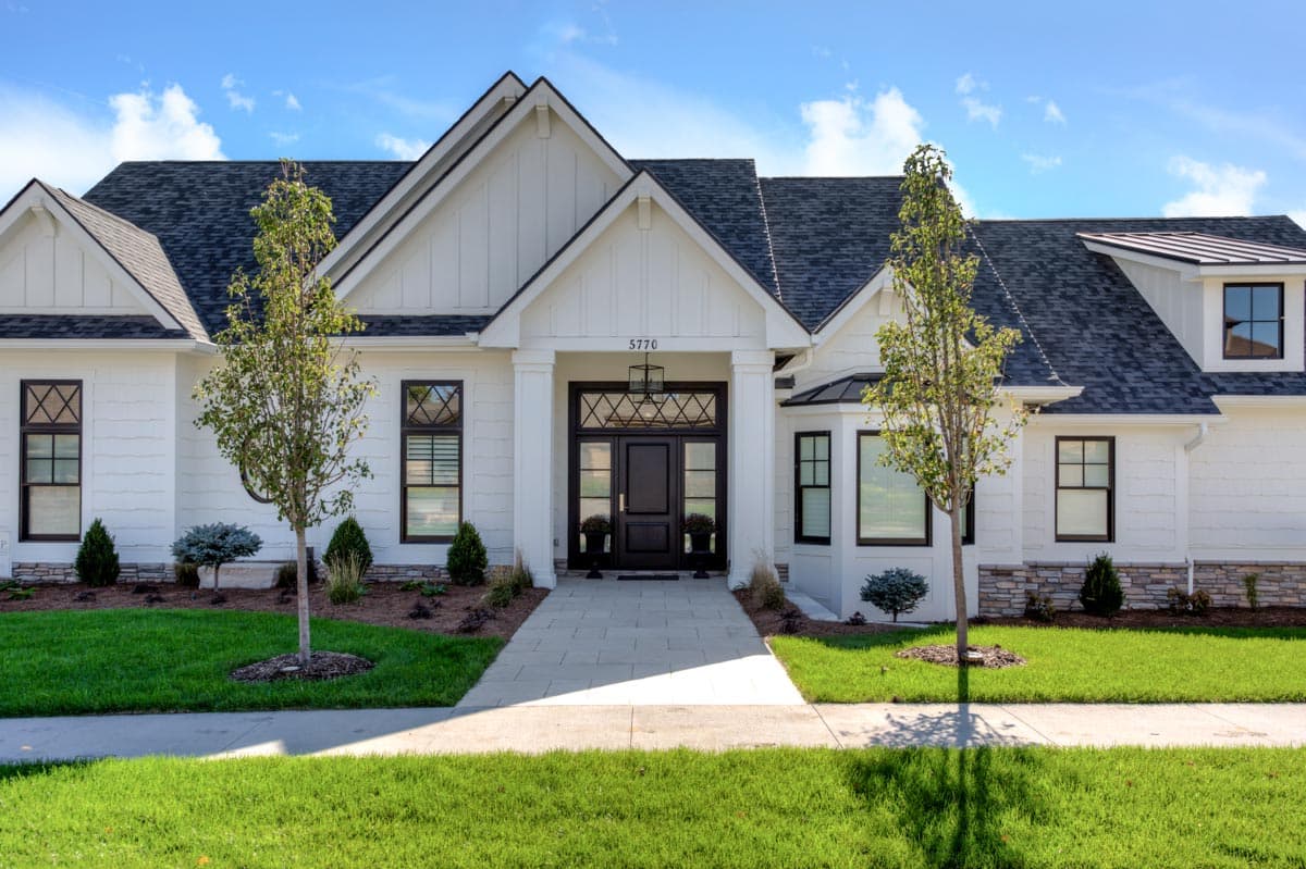 House plan exterior: Modern Farmhouse style, two stories, white siding, board and batten accents, prominent gables, covered entryway, dark metal roof.