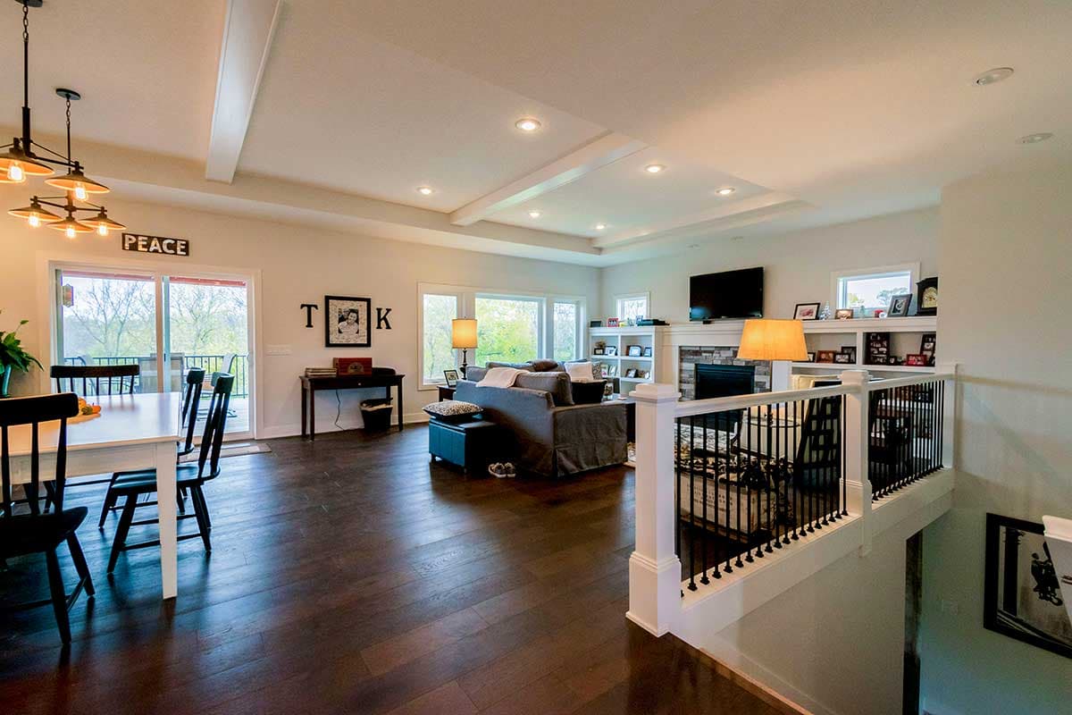 Open concept living and dining area with coffered ceiling, fireplace, and built-in shelving.
