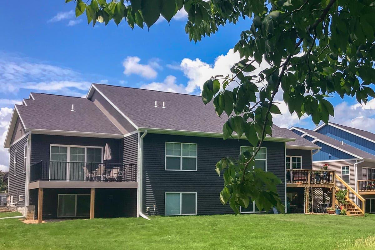 House plan exterior with dark siding, multiple gables, and a deck with railings.