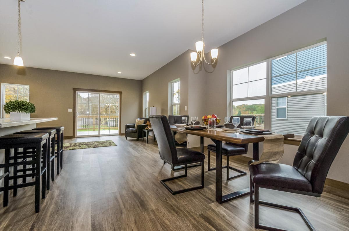 Open-concept dining and living area with a kitchen island, dining table, and slider door to a deck.