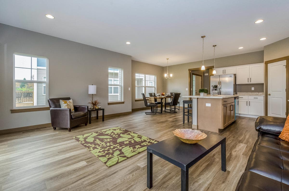 Open concept living area with kitchen island, dining table, and seating area with leather sofa.