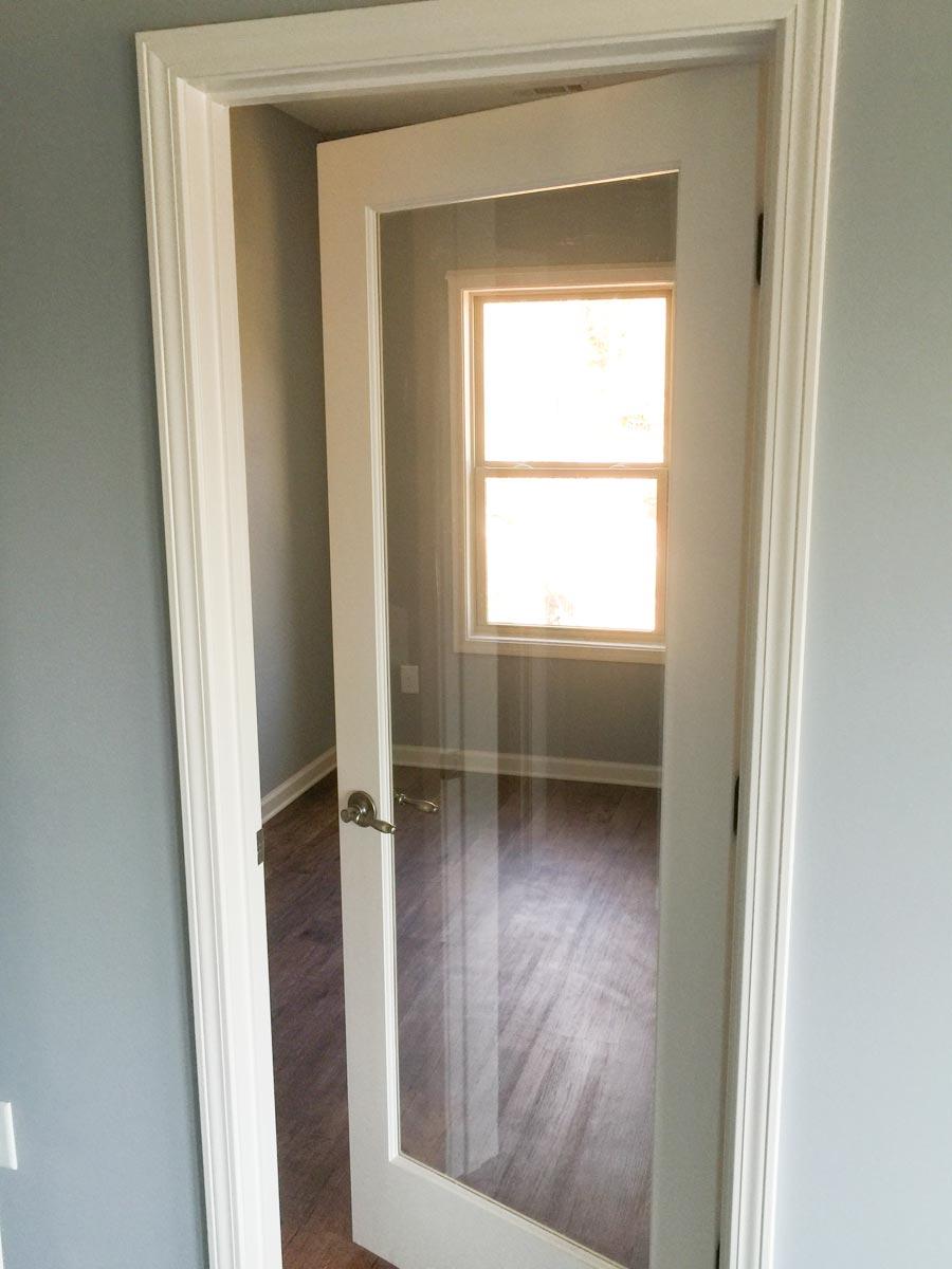 Interior view of a room with glass-paneled door, wood flooring, and window.