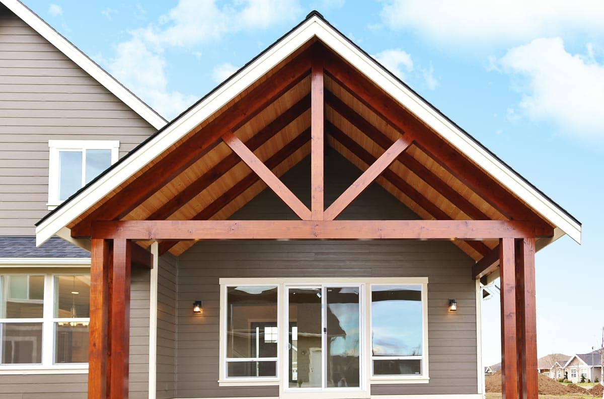 House plan exterior featuring a covered porch with exposed timber trusses and large sliding glass doors.