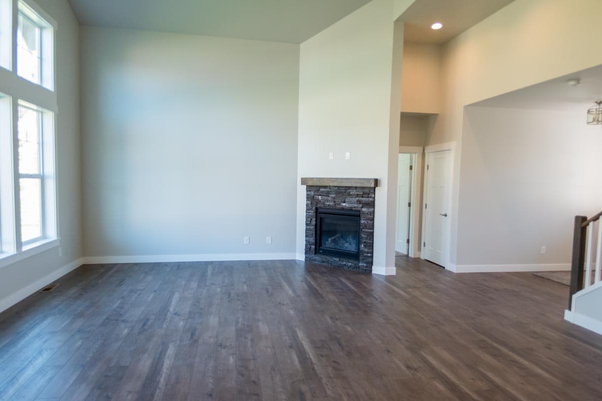 Interior view of living room with stone fireplace, large windows, and vaulted ceiling.