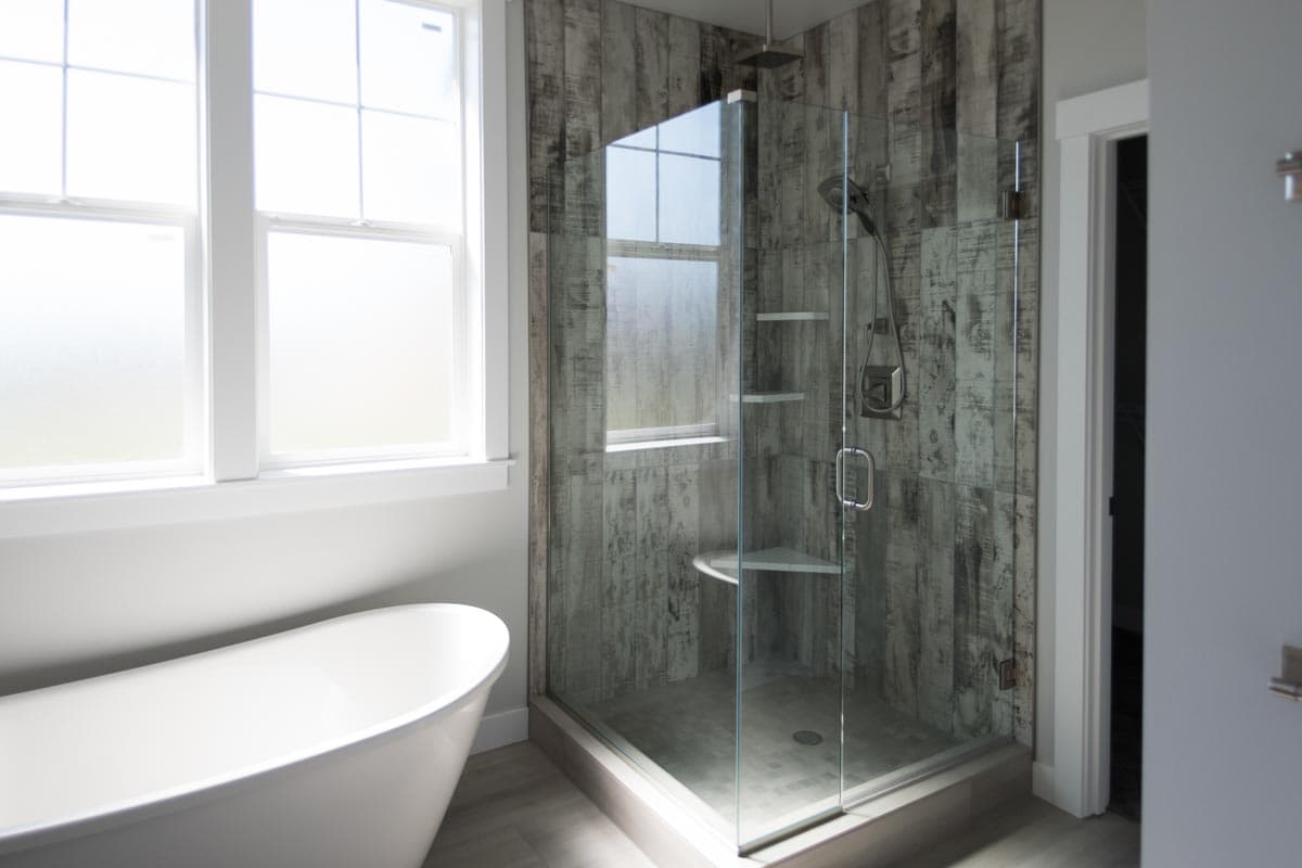Bathroom with freestanding tub and glass-enclosed shower featuring weathered wood-look tile.