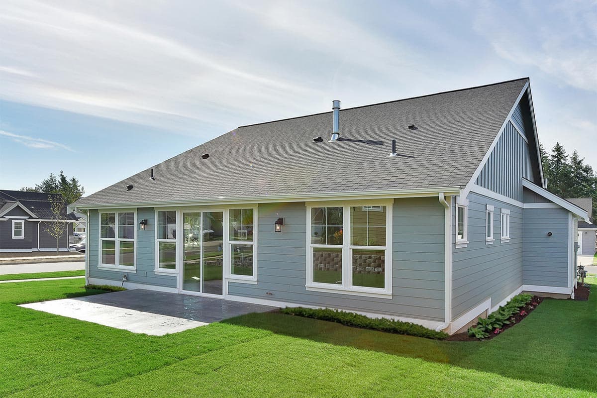 House plan exterior: Ranch style with large windows, sliding glass doors, gable end detail, and asphalt shingle roof.