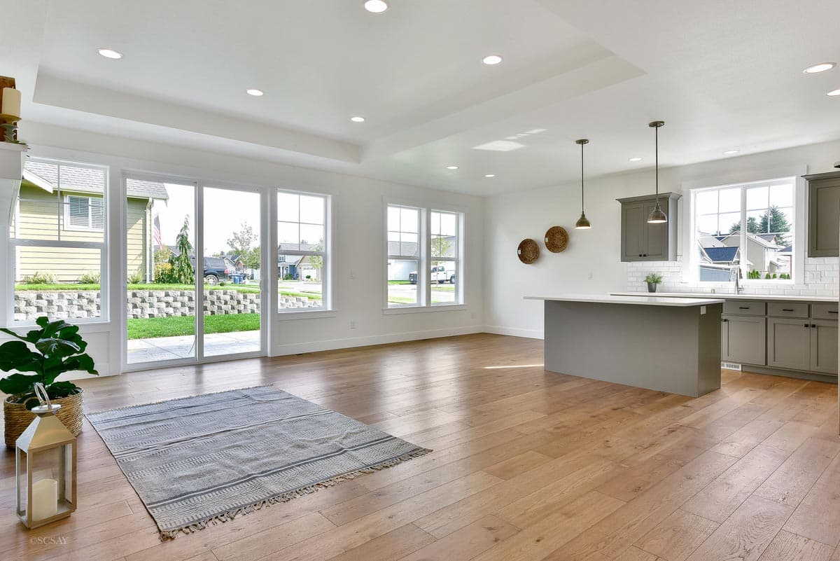Open-concept living and kitchen area with island, recessed lighting, and large windows with backyard access.