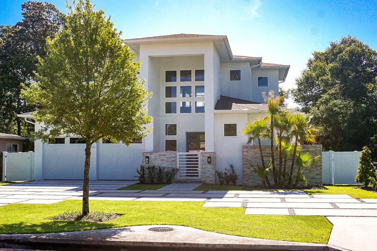Modern house plan exterior: Two-story residence with a multi-story grid window facade, flat roof, and stone accents.