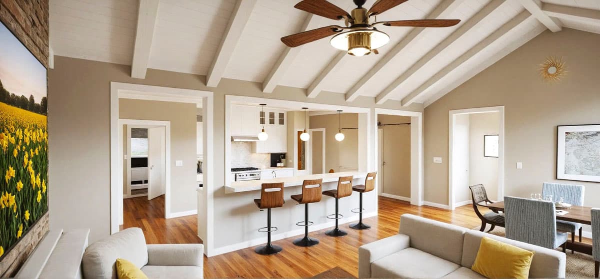 Interior view of a living area with vaulted beamed ceiling, open to a kitchen with island seating and bar stools.