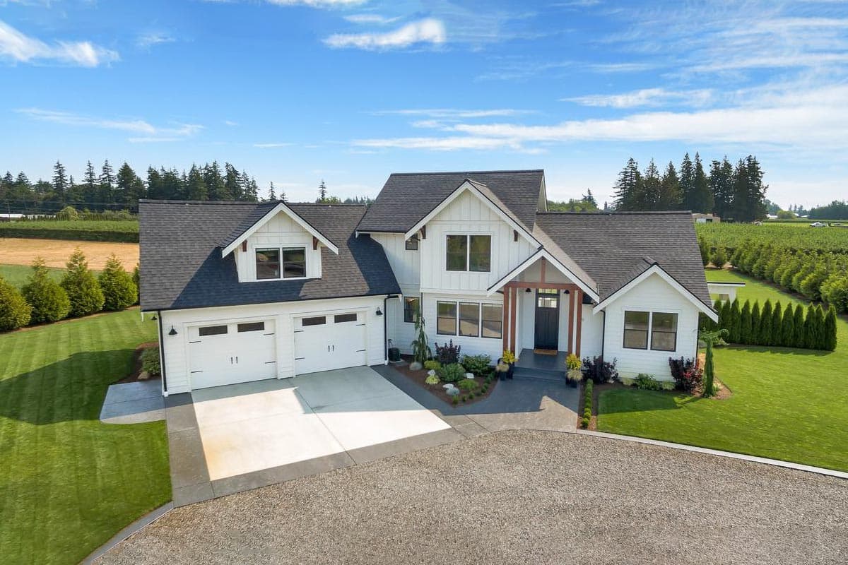 House plan exterior. Two-story Modern Farmhouse with gabled roof, dormers, and a covered porch entry. Includes a two-car garage.