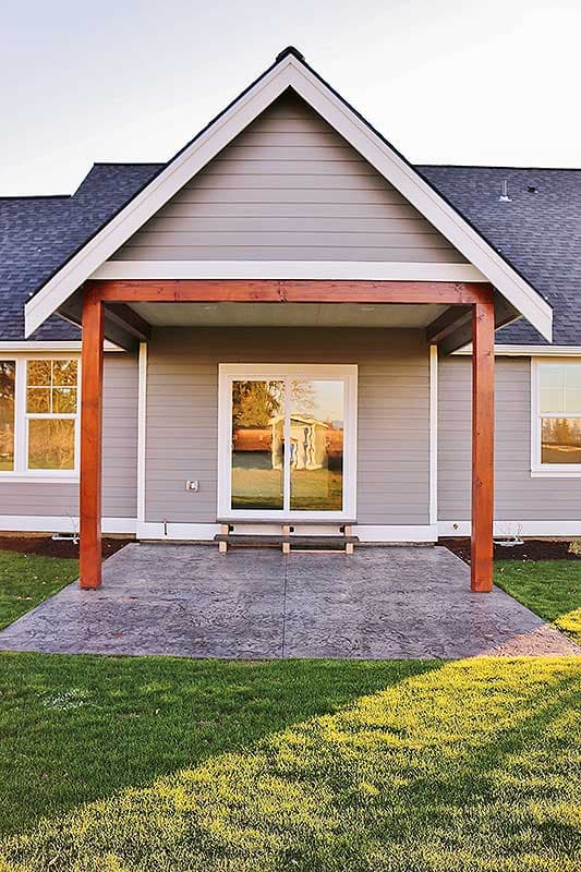 House plan exterior: Covered patio with wood posts, siding, gable roof, and sliding glass door.