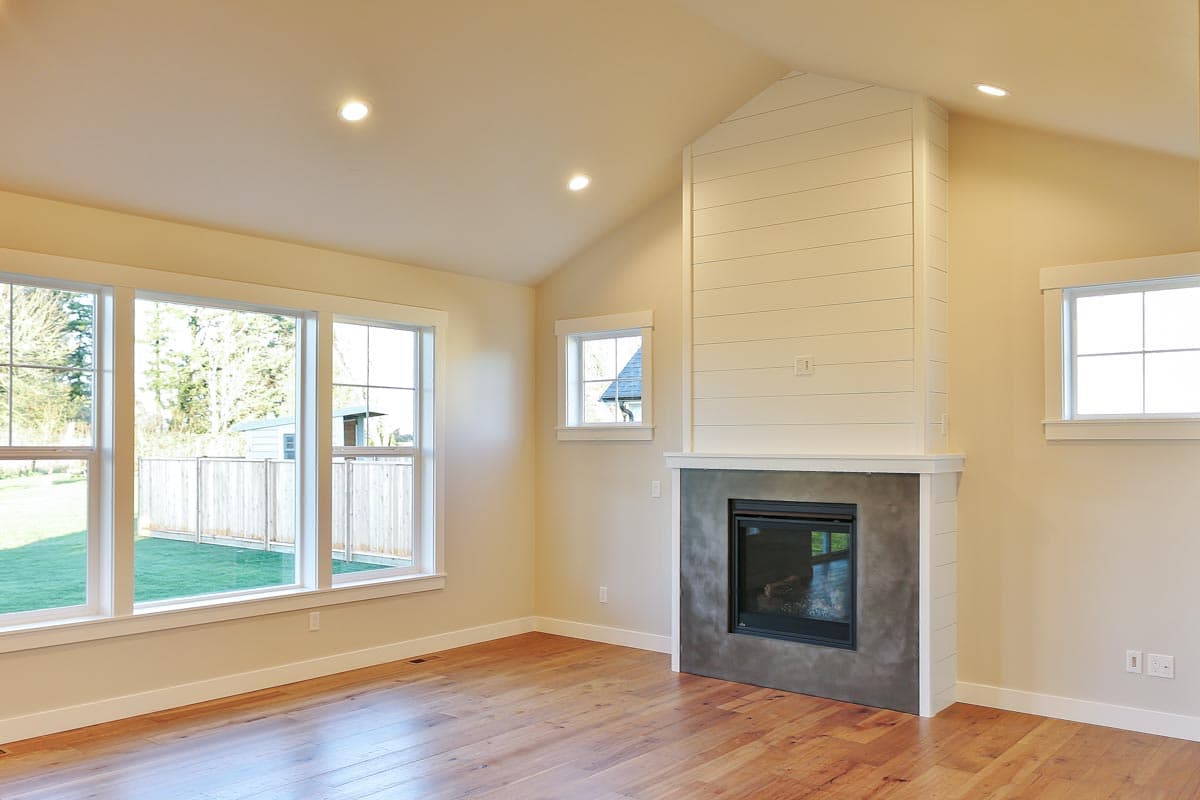 Interior rendering of a room with vaulted ceiling, shiplap fireplace, and large windows.