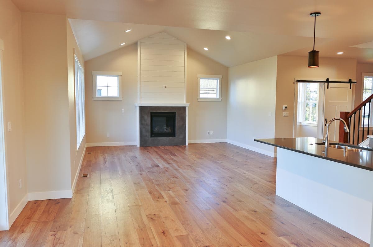 Open concept living area with vaulted ceiling, fireplace, kitchen island with sink, and barn door.