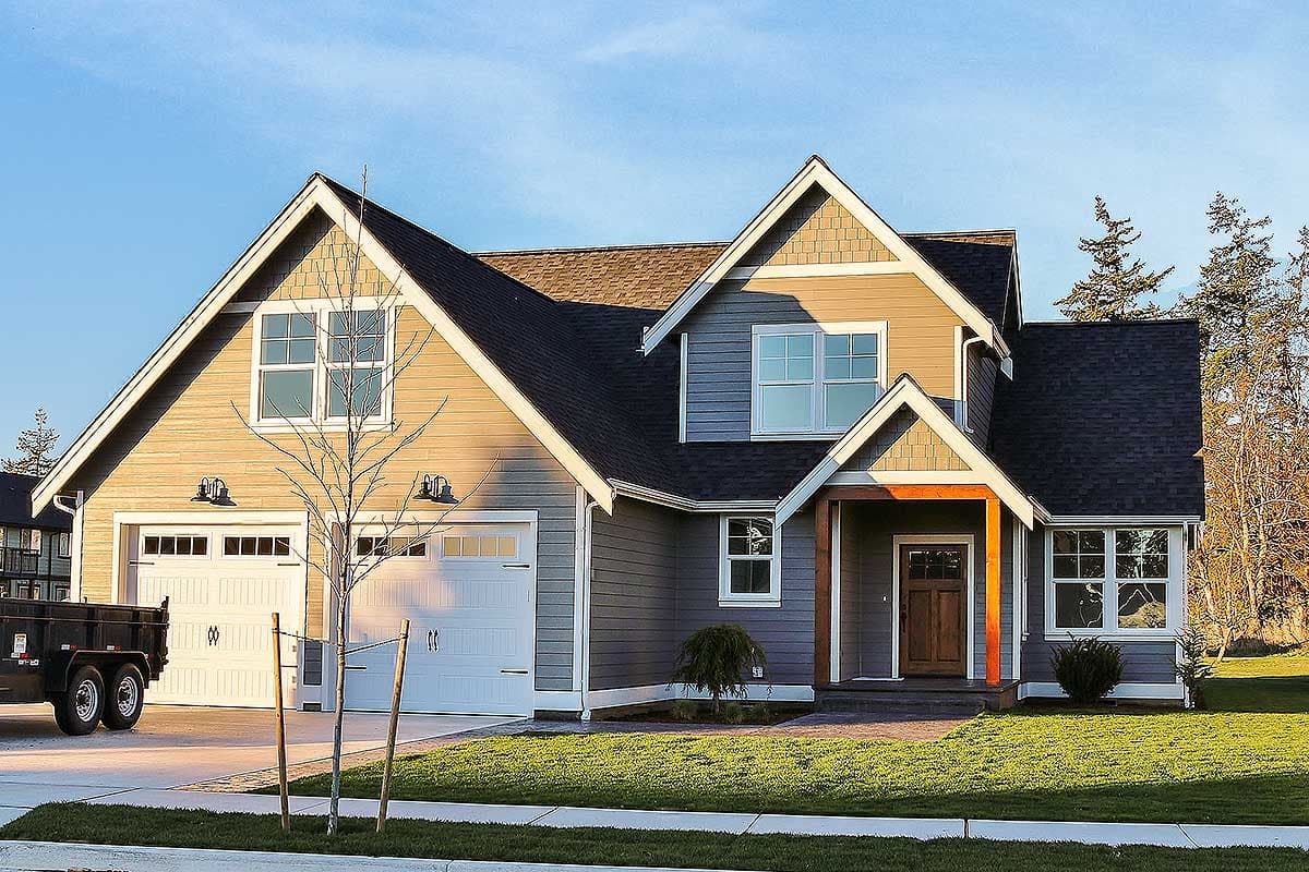 House plan exterior: two-story home with dual garage doors, prominent gables, covered entry with wood accents, and contrasting siding.