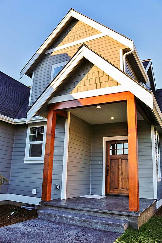 House plan exterior: Two-story home with gabled rooflines, shingled gable ends, covered porch, and wood front door.