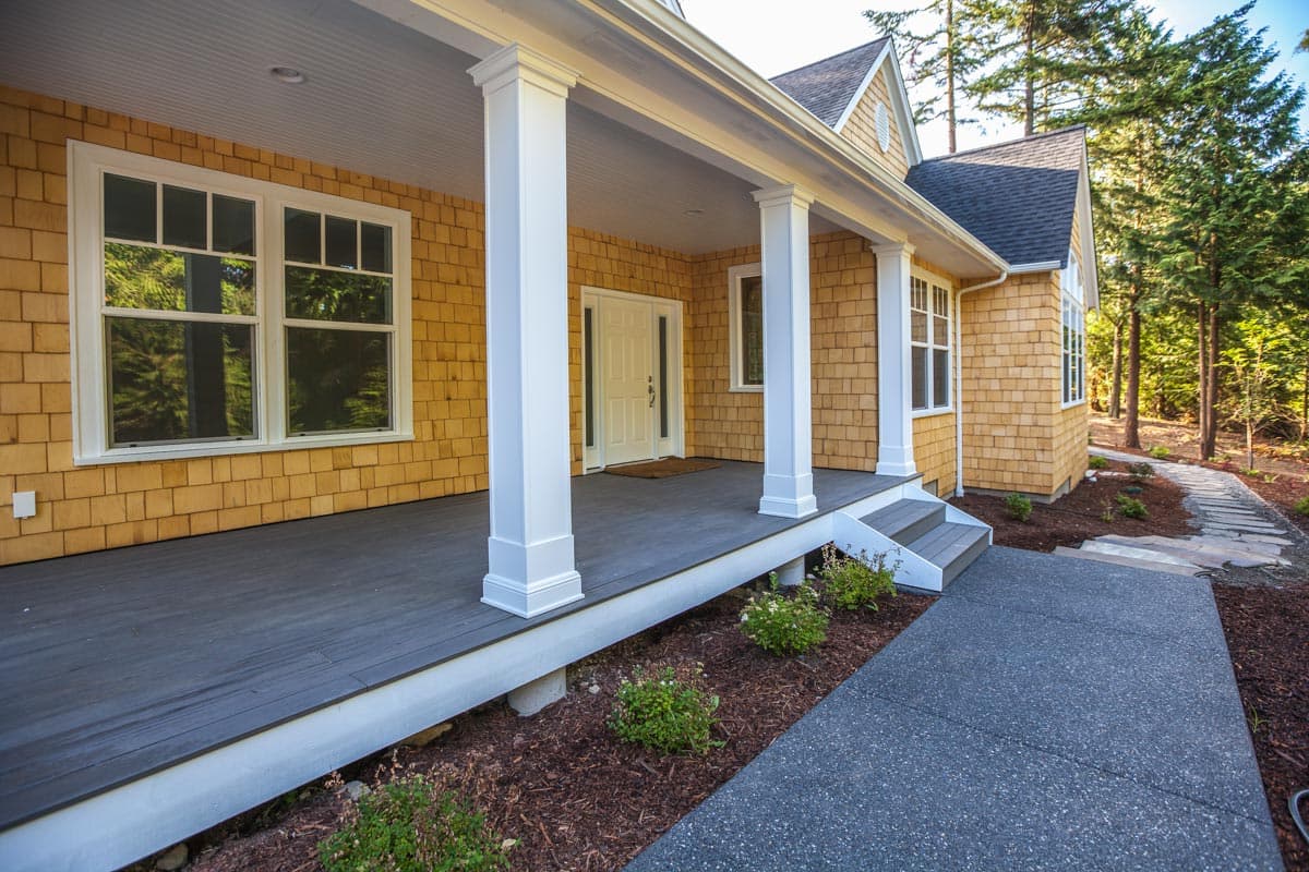 House plan exterior features shingle siding, a covered porch with square columns, and a gray composite deck.
