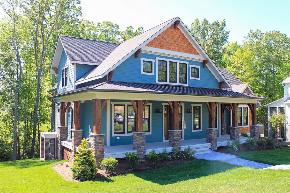 House plan exterior: Two-story modern farmhouse with wrap-around porch, stone pillar bases, and cedar shake gable.