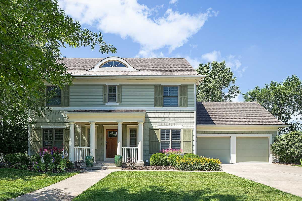 Two-story house plan exterior with a covered porch, dormer window, and attached two-car garage.