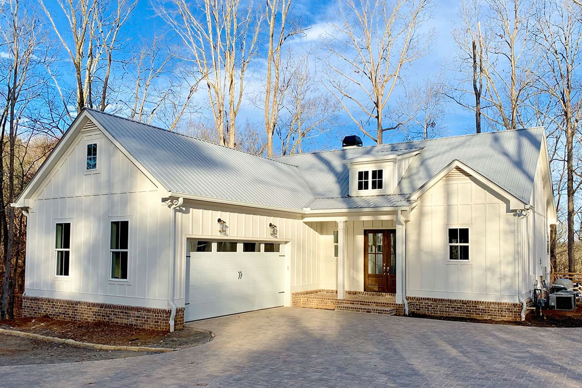 House plan exterior. Modern Farmhouse style with a single story, metal roof, gabled dormers, and a two-car garage.