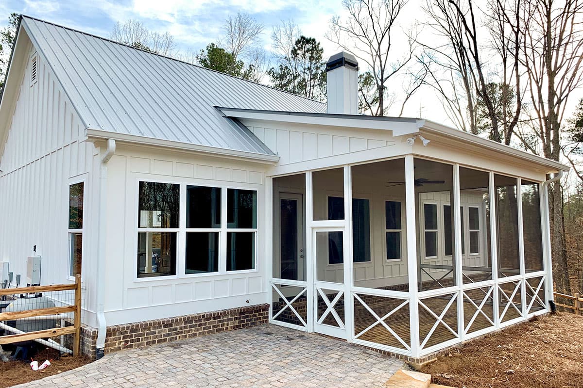Modern Farmhouse exterior: white board and batten siding, metal roof, large windows, and screened porch with X-braced railings.