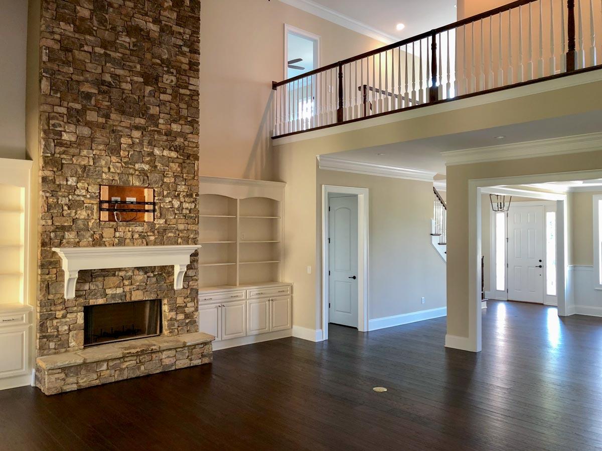 Great room with two-story stone fireplace, built-in shelving, and an open loft overlooking the main floor.