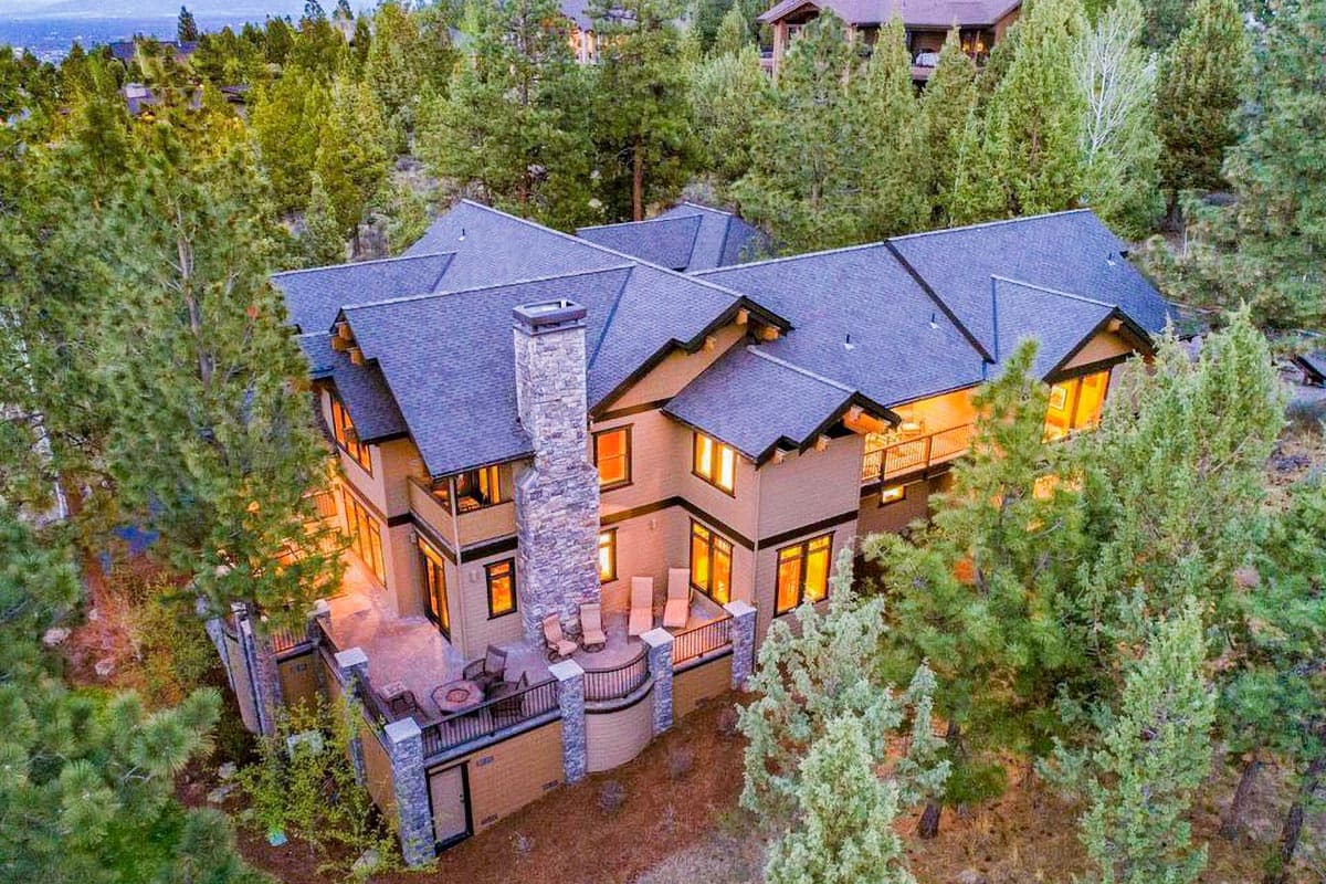 House plan exterior, two stories, with stone chimney, multi-level decks, and multiple gables.