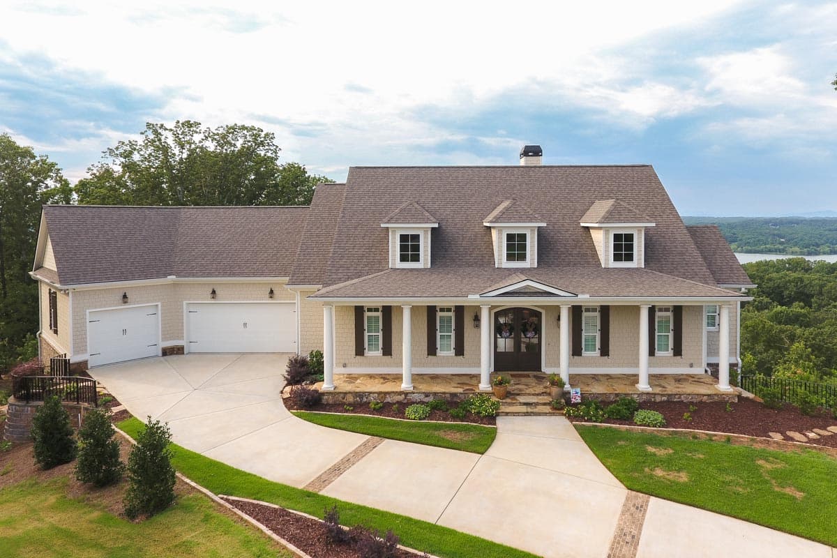 House plan exterior: two-story Modern Farmhouse with wraparound porch, dormers, and a three-car attached garage.