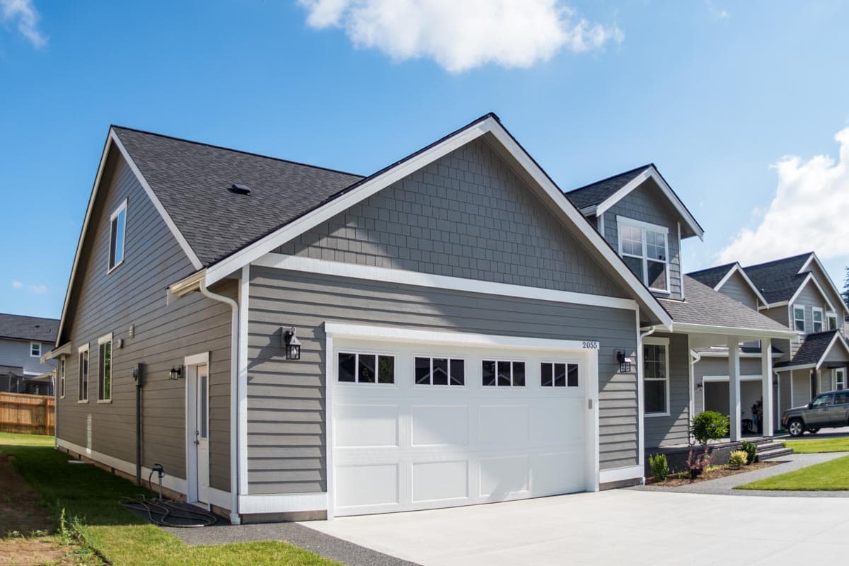 House plan exterior: two-story modern farmhouse with vinyl siding, gables, dormers, and a large garage door.