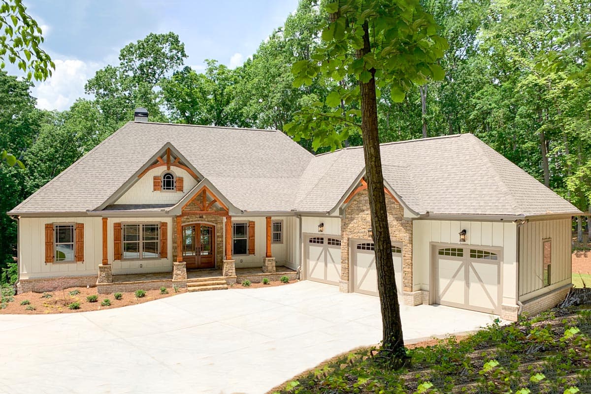 House plan exterior. Craftsman style with a single story, gable roof, stone accents, and a three-car garage. Features include wooden shutters.