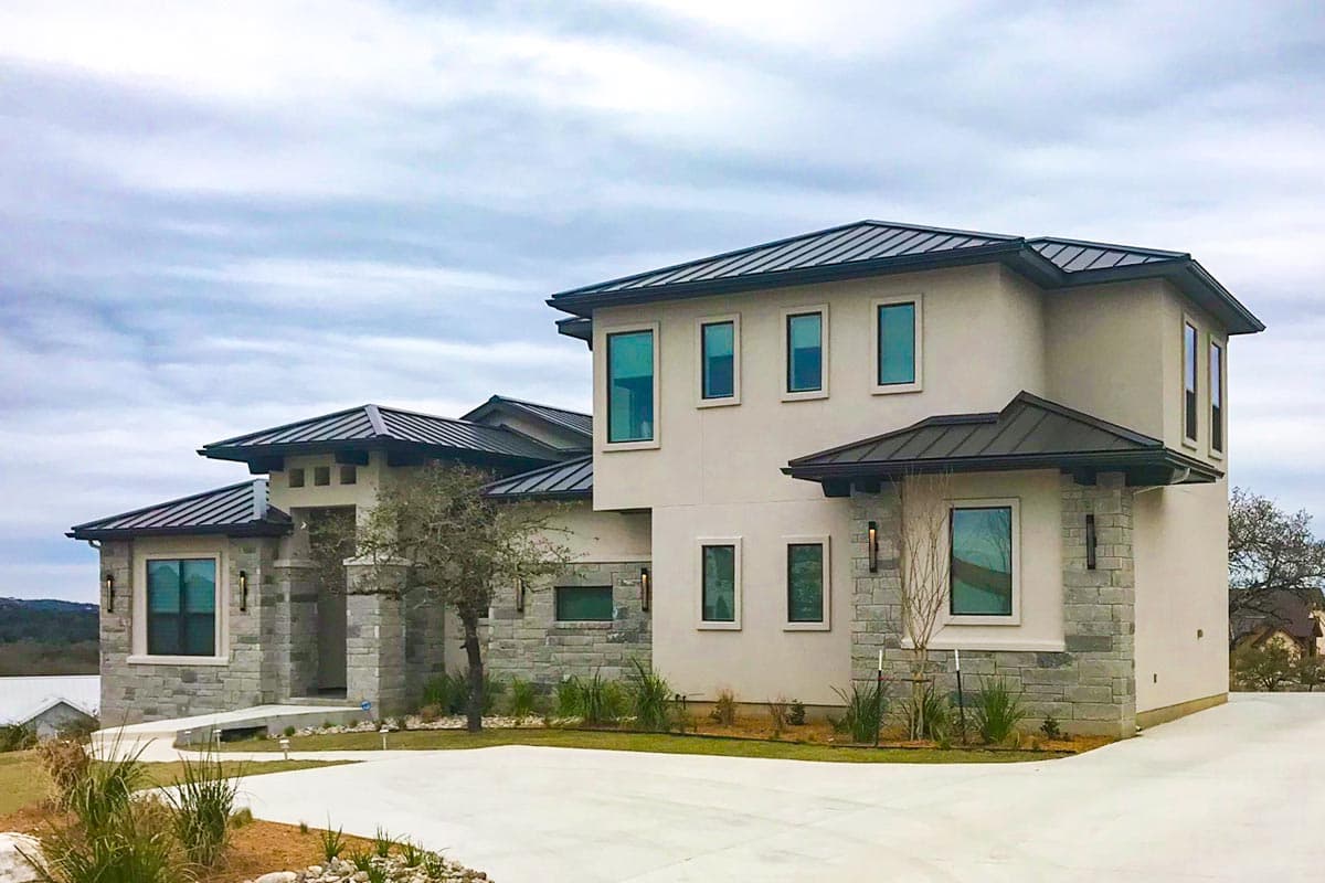 House plan exterior, two stories, modern style, metal roof, stone accents, multiple gables, and large windows.