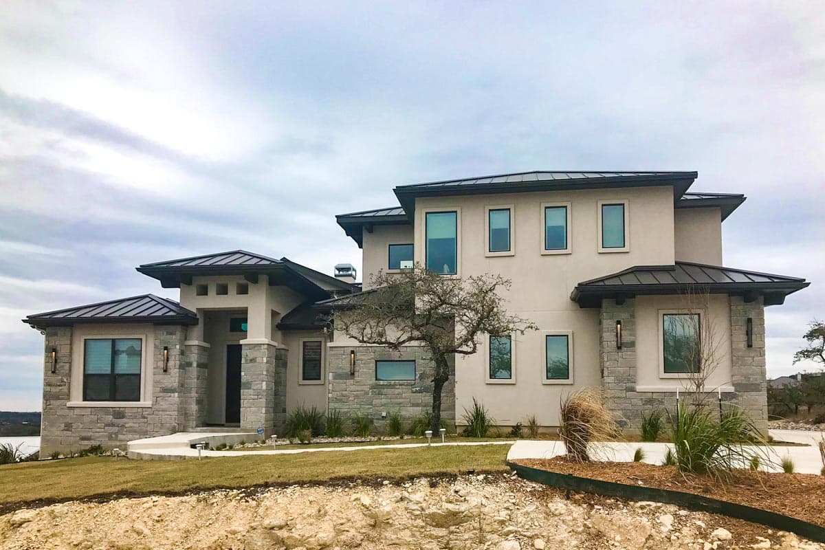 House plan exterior of a two-story modern home with stone accents, multiple gables, and a metal roof.