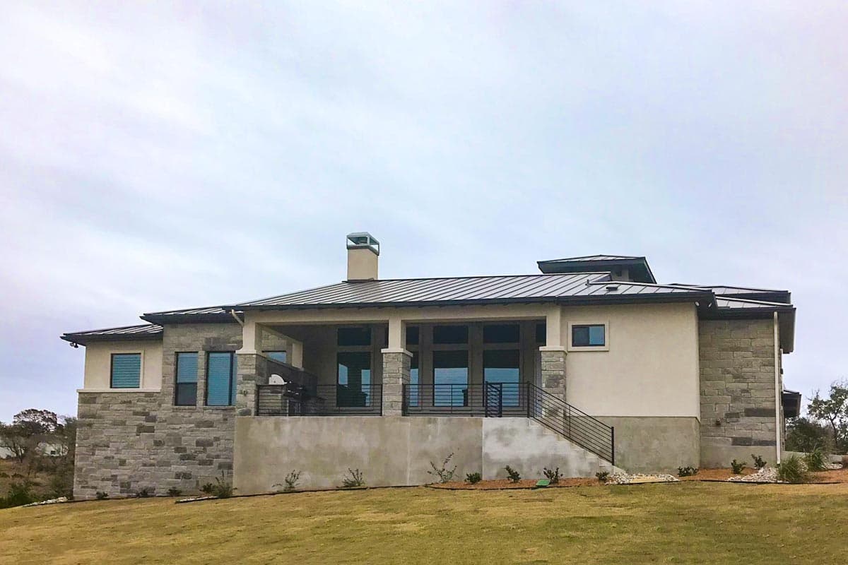 Modern house plan exterior with stone and stucco, large windows, covered patio, and metal roof.