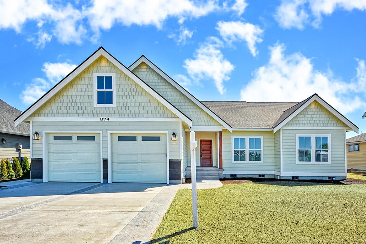 House plan exterior. Craftsman style, one story home with a gable roof, shake siding, and an attached two-car garage.