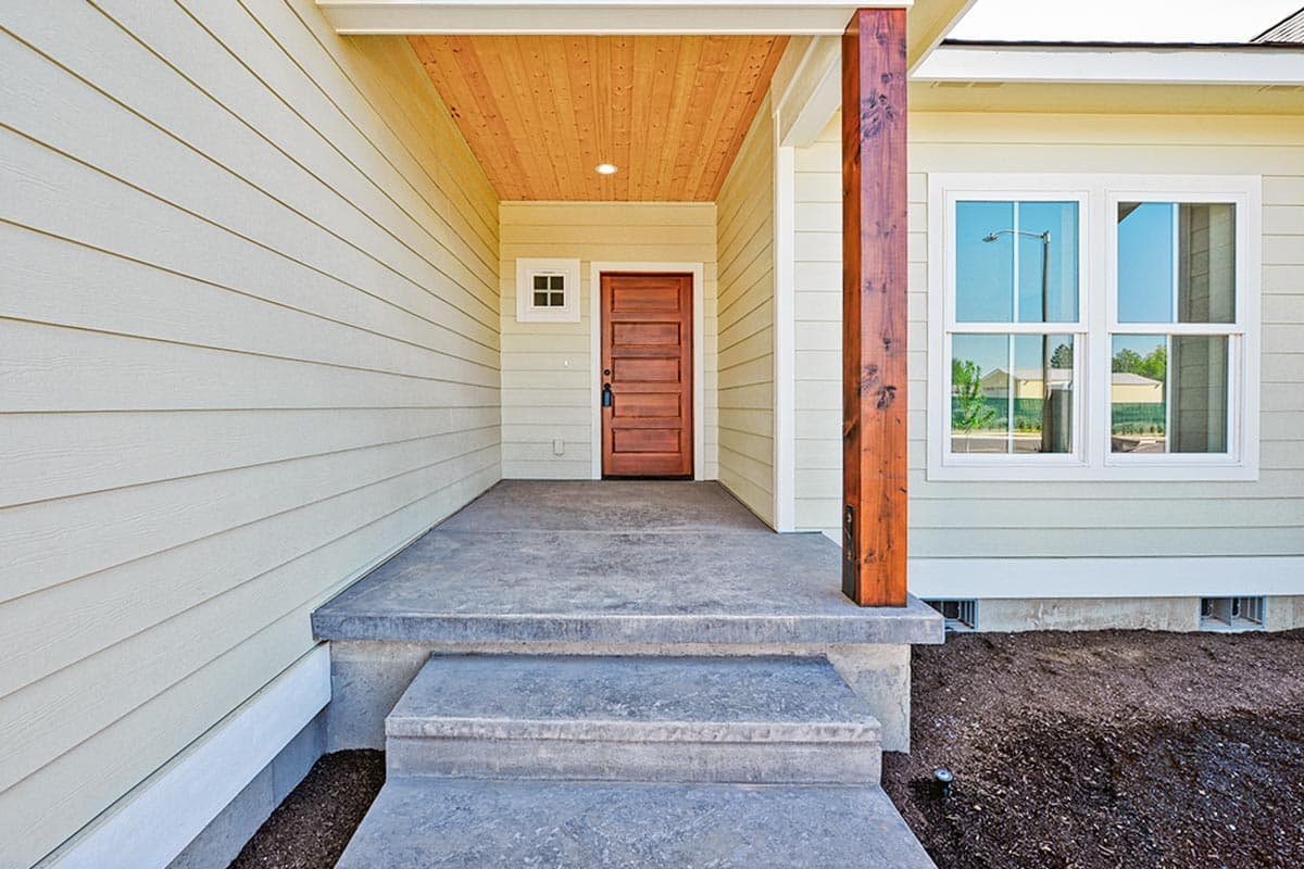 House plan exterior with wood-paneled porch ceiling, wood front door, and two-story windows.