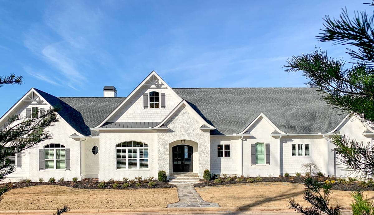 House plan exterior: Single-story Modern Farmhouse with white brick, prominent gables, arched entryway, and metal roof accents.
