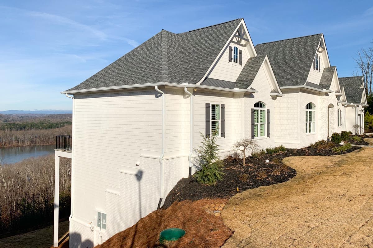 House plan exterior featuring multiple gables, white siding, arched windows with dark shutters, and a grey shingle roof.