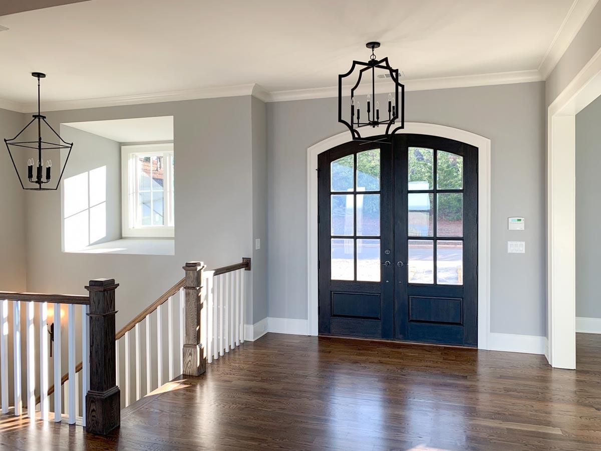 Interior view of entryway with arched double doors, staircase, and geometric pendant lights.